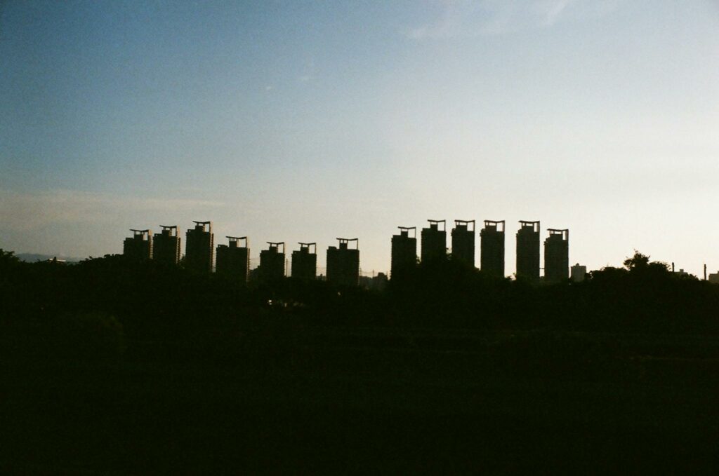 Silhouette of tall buildings against the sunset sky, creating a serene urban skyline.