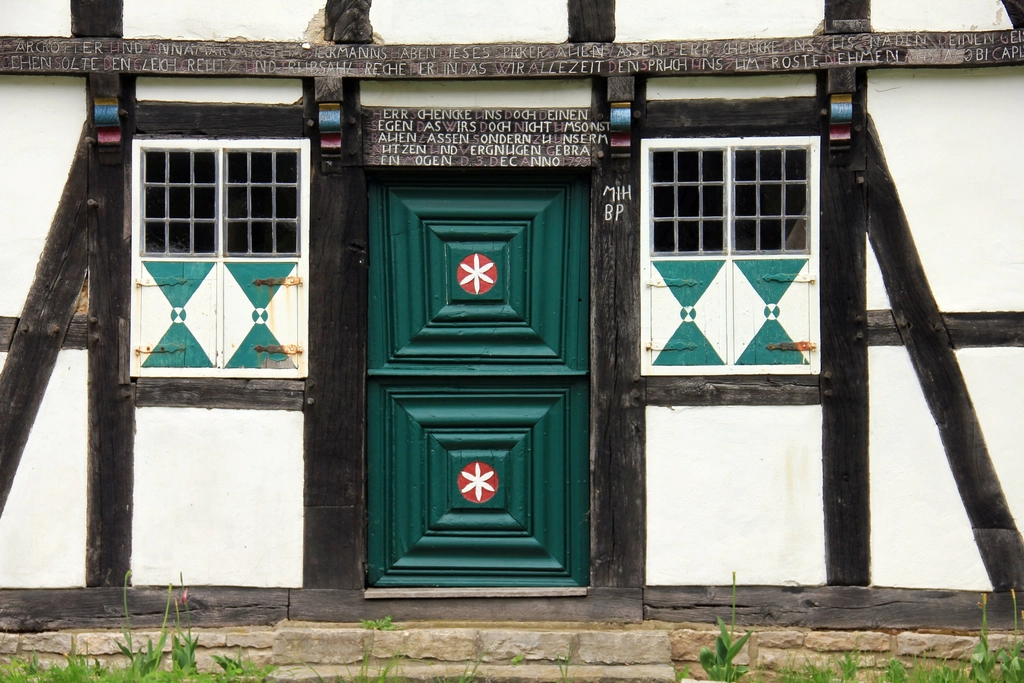 Façade d'une maison ancienne à colombages avec une porte en bois verte